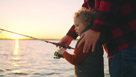 Un-Niño-Caucásico-Rizado-Está-Aprendiendo-A-Pescar,-Su-Padre-O-Su-Abuelo-Le-Están-Enseñando-Una-Familia-Feliz