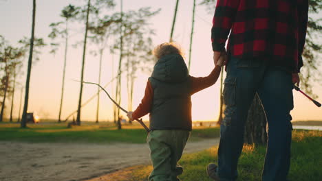 cute-little-child-is-holding-hand-of-grandfather-or-dad-walking-together-to-fishing-in-sunset-time