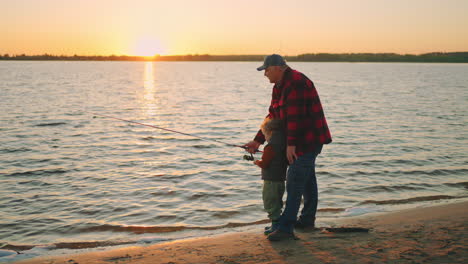 beautiful-sunset-on-river-old-fisher-and-little-boy-are-catching-fish-granddad-and-child-are-spending-weekend