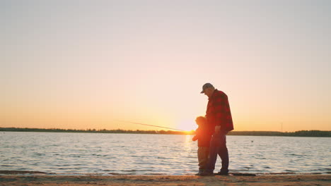 Opa-Und-Enkel-Angeln-Im-Sonnenuntergang.-Alter-Fischer-Und-Kleiner-Junge-Fangen-Fische