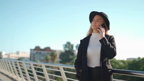 Mujer-Joven-Hablando-Por-Teléfono-Móvil-En-El-Puente-Bajo-La-Luz-Del-Sol