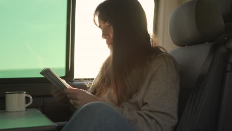 Traveling-woman-reading-book-in-van-at-sunset