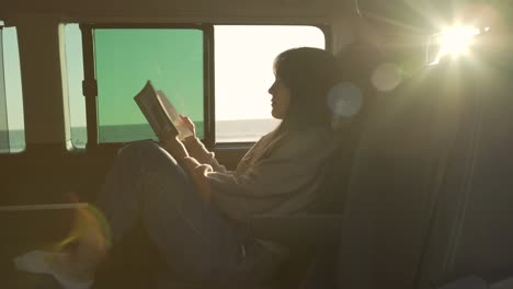 Mujer-Viajera-Leyendo-Un-Libro-En-Una-Camioneta-Al-Atardecer