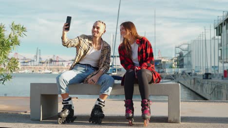 Cheerful-man-taking-selfie-on-smartphone-with-girlfriend-on-embankment