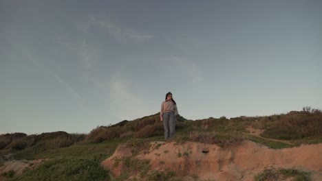 Traveling-woman-standing-on-hill-at-sunset