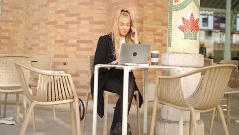 Frau-Spricht-Auf-Dem-Smartphone,-Während-Sie-Im-Café-Mit-Einem-Laptop-Arbeitet
