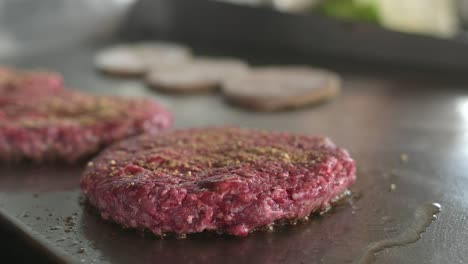 Crop-cook-grilling-hamburger-buns-and-cooking-cutlets-in-kitchen