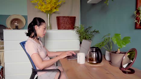 Asian-woman-reading-document-on-laptop-and-working-at-home