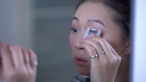 Charming-ethnic-woman-using-eyelash-curler