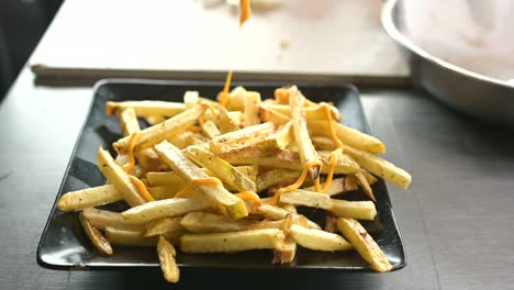 Unrecognizable-cook-adding-cheese-sauce-on-French-fries