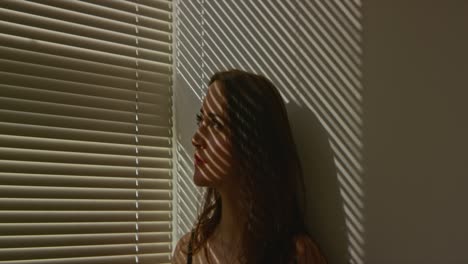 Woman-peeking-out-through-blinds