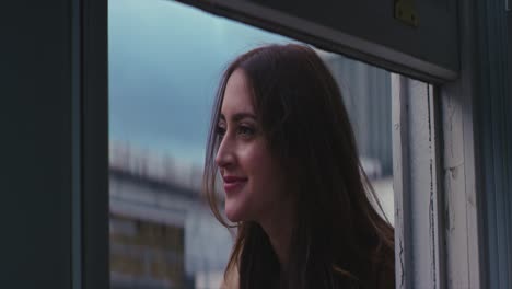 woman-smiling-leaning-out-of-window-view-from-inside