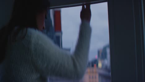 Woman-opening-window-in-apartment-at-night