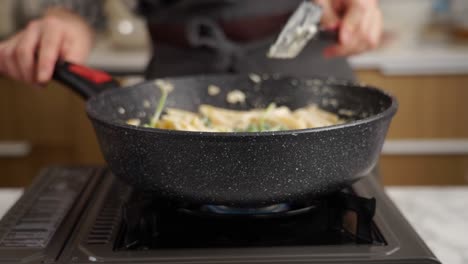 Crop-housewife-preparing-pasta-in-frying-pan