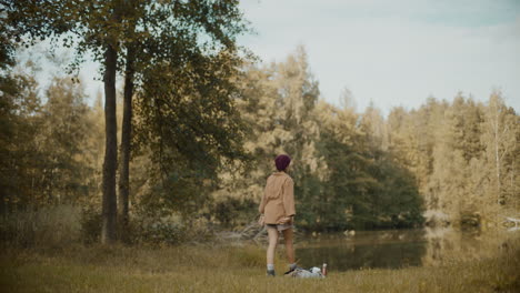 Woman-walking-towards-lake-in-forest