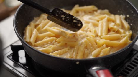 Cook-stirring-cream-to-boiling-pasta