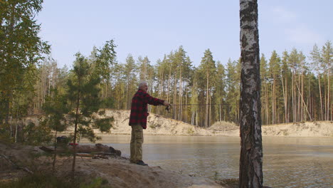 Un-Hombre-Relajado-Disfruta-Pescando-En-Un-Lugar-Ecológico-Lanzando-Caña-En-El-Agua-De-Un-Lago-Limpio-Descansando-Solo-En-El-Bosque