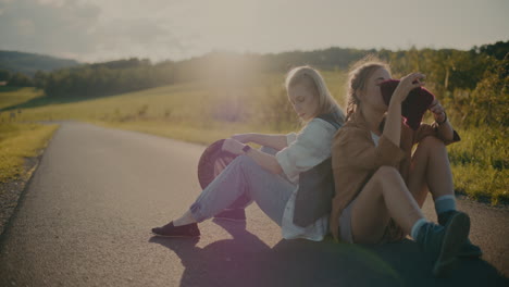 Bored-Women-With-Hats-Sitting-On-Road-Near-Meadow