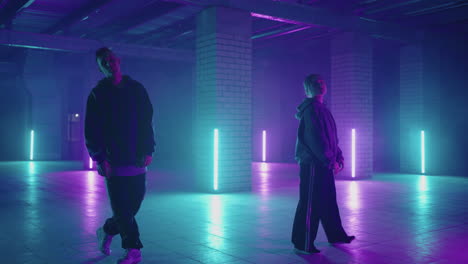 Professional-Hip-Hop-break-dancers-.-Stylish-young-couple-dancing-with-real-strobe-lights-.-Against-blue-background-of-led-lights.-Dancing-young-couple-in-colourful-neon-studio-light-hip-hop-dancers