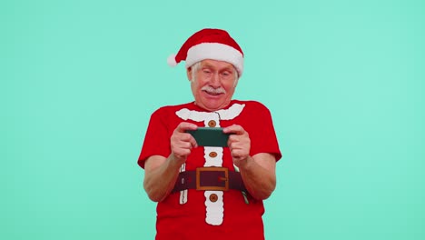 Besorgter-Großvater-Im-Weihnachts-T-Shirt-Spielt-Begeistert-Rennvideospiele-Auf-Dem-Handy