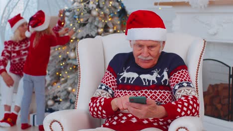 El-Anciano-Abuelo-Compra-Regalos-De-Navidad-Haciendo-Compras-En-Línea-Por-Teléfono-Móvil-En-Casa