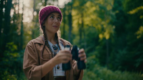 Woman-Wearing-Knit-Hat-Looking-Through-Binocular-In-Forest