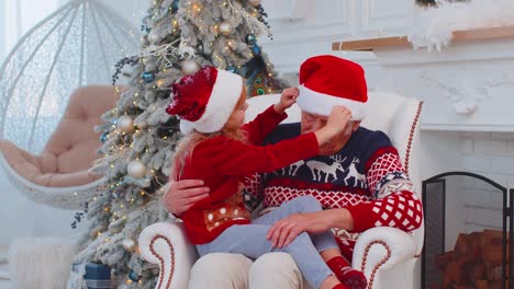 Enkelkind-Mädchen-Kind-Repariert-Weihnachts-Weihnachtsmann-Mütze-Auf-Glücklichem-älteren-Alten-Lächelnden-Großvater-Zu-Hause