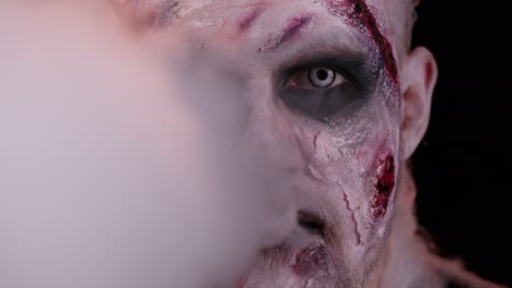 Erschreckender-Mann-Mit-Halloween-Zombie-Make-up-Bläst-Rauch-Aus-Nase-Und-Mund-Und-Versucht,-Angst-Zu-Machen