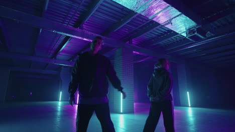 A-duet-of-two-professional-dancers-a-man-and-a-woman.-A-stylish-couple-dances-hip-hop-freestyle-together-in-synchronously-in-lard-lit-in-blue-purple-hues-with-neon-light