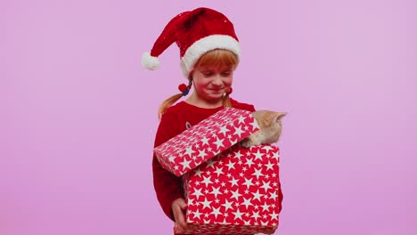 Girl-in-Christmas-red-sweater-hat-smiling,-unwrapping-gift,-opening-box-with-pet-cat,-great-surprise