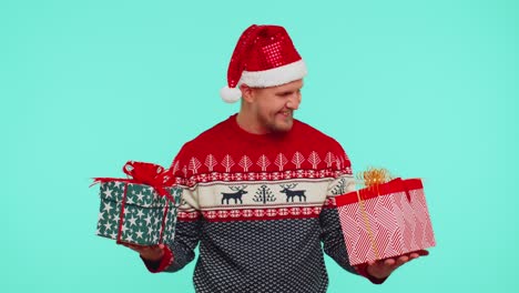 Cheerful-man-in-Santa-sweater-presenting-two-Christmas-gift-boxes,-stretches-out-his-hands-to-camera
