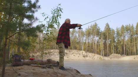 spin-fishing-of-middle-aged-man-in-forest-lake-man-is-casting-rod-and-rotating-reel-during-angling-relax-and-enjoy-wild-nature