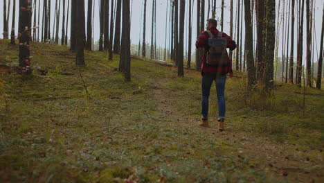 A-young-man-walks-uphill-from-the-forest-in-autumn-in-slow-motion-with-a-backpack.-A-hipster-man-in-a-plaid-jacket-walks-through-a-beautiful-woodland-area-in-an-autumn-Park.-High-quality-4k-footage