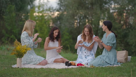 A-group-of-young-women-in-nature-together-sculpt-from-clay.-Open-class-joint-activity-communication-laughter-common-hobby-women's-circle.