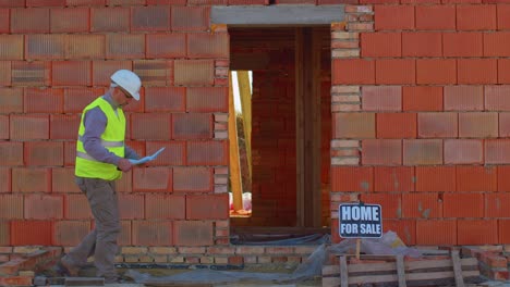 Professional-builder-worker-architect-analyzes-blueprints,-dimensions-at-construction-house-site
