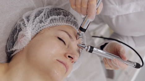 Frau-Mittleren-Alters-Erhält-Von-Einer-Kosmetikerin-Im-Salon-Eine-Gesichts-Stirn-Hautbehandlung-Mit-Mikroströmen