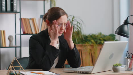 Müde-Kaukasische-Geschäftsfrau,-Die-Im-Büro-Unter-Kopfschmerzen,-Spannung,-Migräne-Und-Stress-Leidet