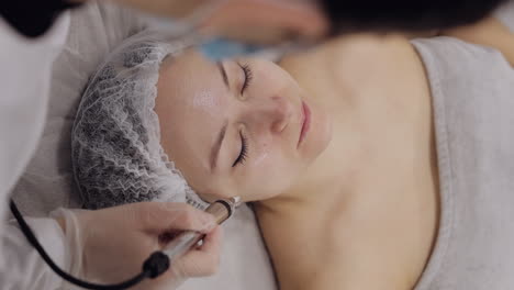 Middle-aged-woman-receiving-micro-currents-facial-skin-treatment-from-beautician-in-spa-clinic