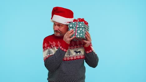 Funny-man-wears-Christmas-sweater-with-deers-received-present,-interested-in-what-inside-gift-box