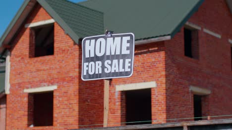 Haus-Zum-Verkauf-Schild-Inschrift-Notiz-Tag-Nachricht-Auf-Papier,-Haus-Im-Hintergrund,-Werbung-Verkaufen