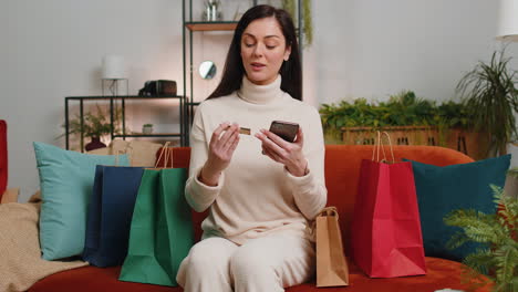 Glückliches-Shopaholic-Junges-Frauenmädchen,-Das-Mit-Einkaufstüten-Sitzt-Und-Online-Mit-Kreditkarte-Bezahlt