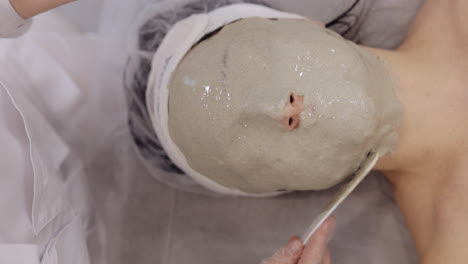 Beautician-applying-medical-peeling-face-mask-on-middle-aged-woman,-skin-care-procedure-in-spa-salon