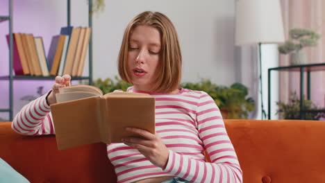 Young-woman-relaxing-interesting-book-turning-pages-smiling-enjoying-literature-taking-rest-on-sofa