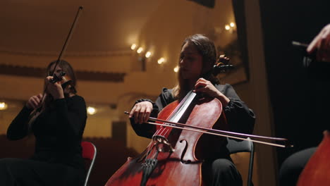 string-instruments-in-symphonic-orchestra-cellist-and-violinist-are-playing-on-scene-of-philharmonic-hall