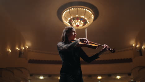 professional-female-violinist-is-playing-violin-on-scene-of-opera-house-portrait-of-soloist-in-philharmonic-hall