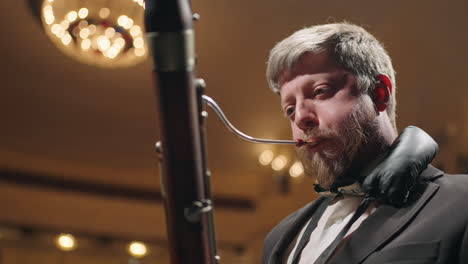 handsome-man-is-playing-bassoon-on-scene-of-opera-house-or-philharmonic-hall-closeup-portrait