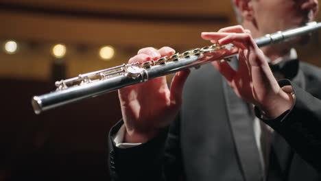 flutist-is-playing-in-symphonic-orchestra-or-brass-band-closeup-view-of-flute-in-male-hands