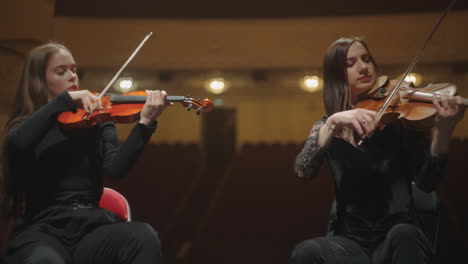female-violinists-are-playing-music-in-orchestra-sitting-on-scene-of-philharmonic-hall