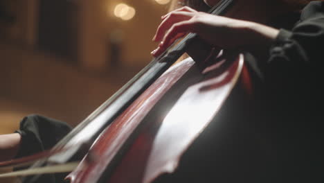 Weibliche-Violoncellistin-Spielt-Violoncello-Auf-Der-Bühne-Nahaufnahme-Von-Cellobogen-Und-Händen-Der-Cellistin