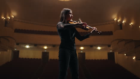 portrait-of-young-woman-with-violin-in-hands-on-scene-of-opera-house-or-philharmonic-hall